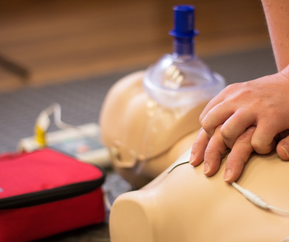 Hands performing chest compressions on a CPR training manikin